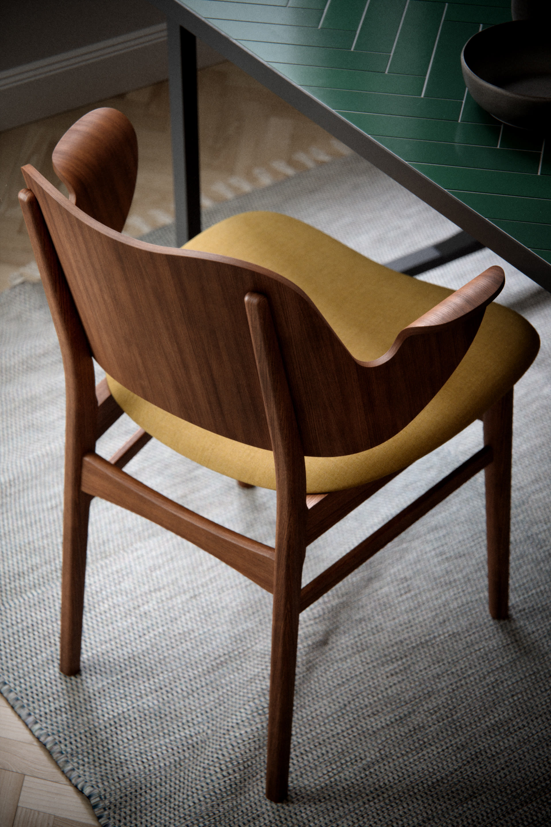 Overhead view of a wooden armchair with a mustard-yellow seat next to a green table, architectural visualization